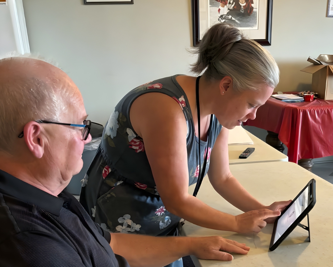 Kasey helps a patient by tapping on a tablet screen.