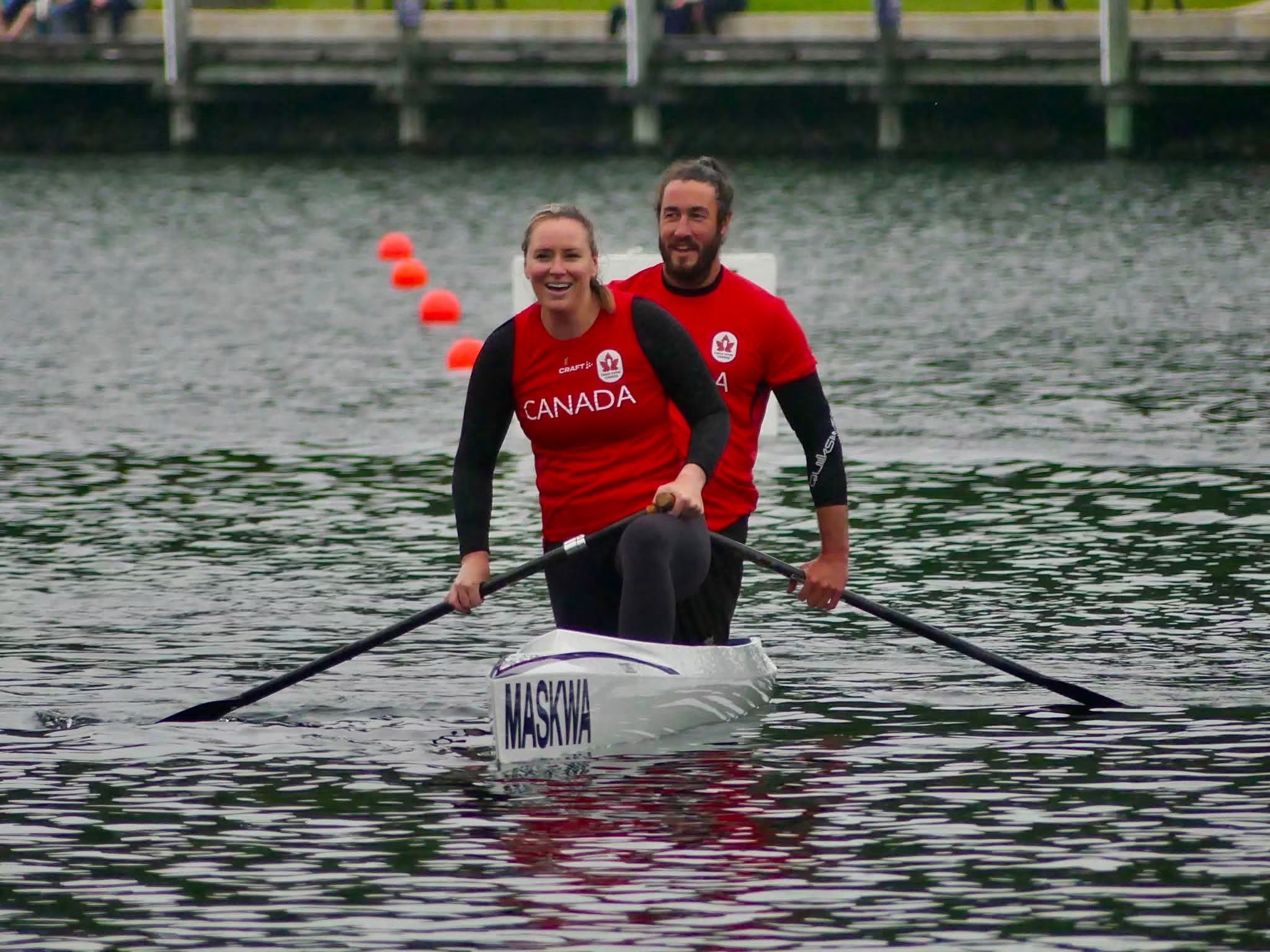 Two people in a kayak on the water wearing red Canada shirts.