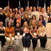 Group of 25 nurses smiling on a stage.