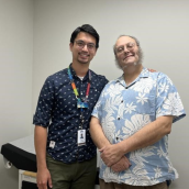 Two men stand smiling at the camera.