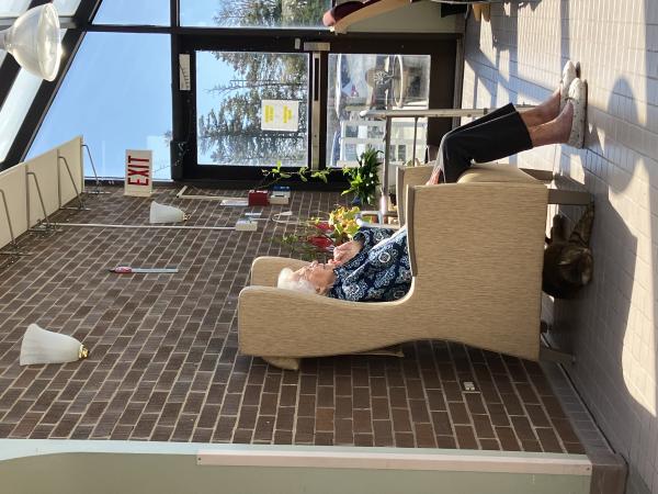 Poppy the cat laying underneath a resident's chair