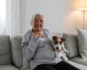 Senior woman sitting on couch with small dog.