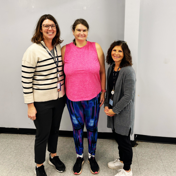 Three women are standing side-by-side, smiling at the camera.