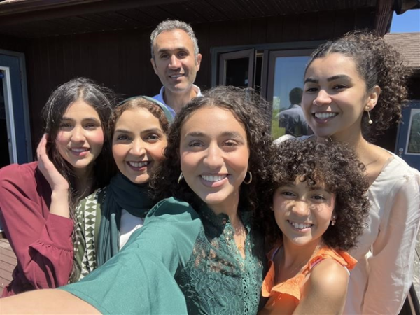 Dr. Abir Hussein, a family physician in Yarmouth, Nova Scotia standing, smiling and taking a selfie with her family  