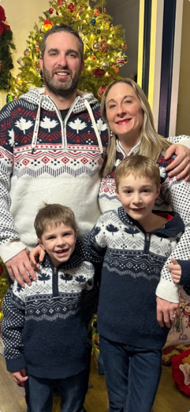 Dr. Andrea Faryniuk, general surgeon in Amherst, Nova Scotia standing and smiling with her partner and two sons